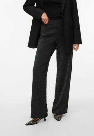 Zwarte, hoog getailleerde broeken met een glinsterende textuur, brede pijpen en zijscheuren, gecombineerd met zwart gepatternde hakken.