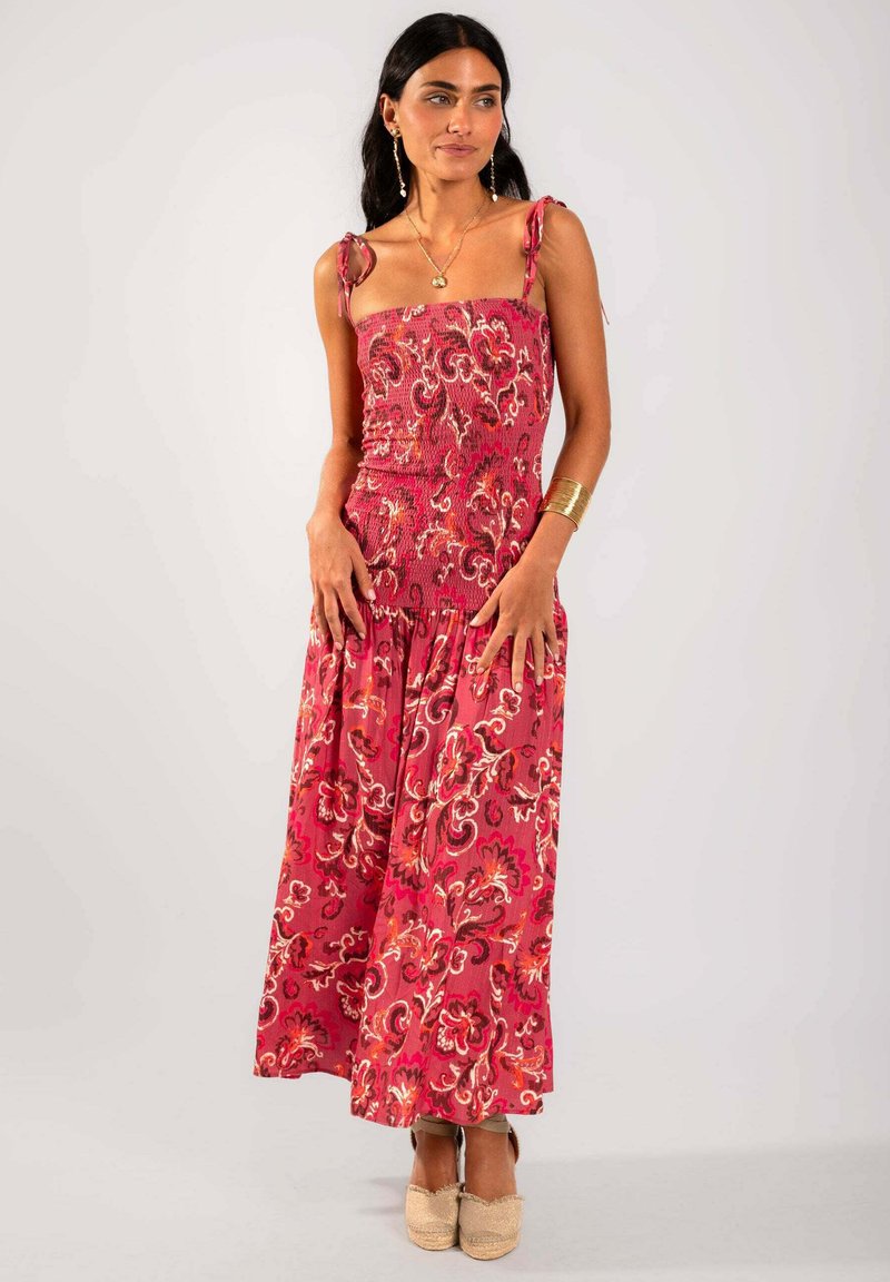 Vestido largo de estampado floral rojo con un cuerpo fruncido, tirantes ajustables y una falda fluida. Presenta una tela ligera y texturada.