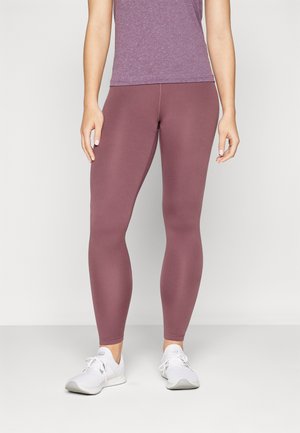 Colanți de culoare mov stins, realizați dintr-un material elastic, cu o textură netedă și un design mulat. Asociați cu încălțăminte sportivă albă.