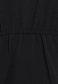 Tessuto nero con una morbida texture, caratterizzato da cuciture arricciate in vita e un drappo fluido sottostante, che crea una forma rilassata.
