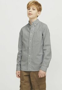 Camicia con bottoni in tessuto a quadri grigi e bianchi, con maniche lunghe, colletto e taschino sul petto. Abbinata a pantaloni cargo marroni.