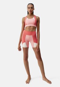Sport bra and shorts set in gradient shades of pink. Smooth texture, high waist, and color blocking with white accents.