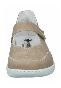 Beige leather shoe with perforated upper, adjustable strap, and white sole. Features contrasting stitching and a rounded toe design.