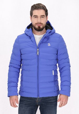 Blauwe gewatteerde jas met een capuchon, textuur met een quiltpatroon, frontale rits, logo op de borst en contrasterende zwarte binnenkant. Draagt over een wit shirt.