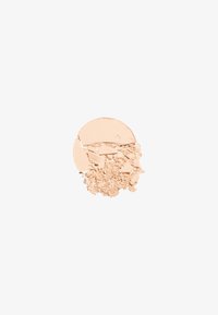 Polvo mineral beige, forma redonda, superficie texturada con partículas finas y gruesas, sobre un fondo blanco.