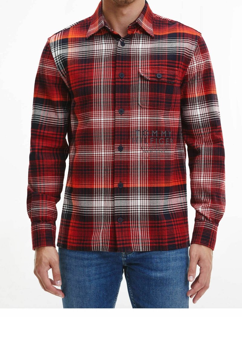 Camicia in flanella a quadri rossa e nera con chiusura a bottoni, colletto a punta e tasca sul petto. Presenta linee bianche a contrasto e tessuto testurizzato.