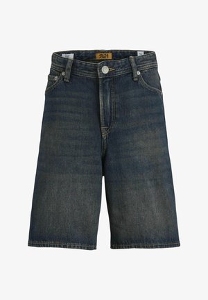 Hvid t-shirt med rund hals, mørke denimshorts og beige sneakers med hvide accenter. Modellen står foran en neutral baggrund.