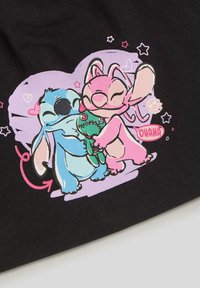 Czarna tkanina z rysunkiem w stylu kreskówki przedstawiającym dwie postacie — niebieską i różową — przytulającą zieloną zabawkę, otoczoną serduszkami i gwiazdkami.