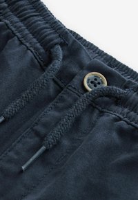 Mørkeblå bomulds shorts med snor i taljen og en knap. Tekstureret stof med syninger og glatte ender på snoren.
