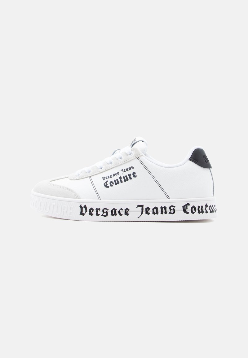 Baskets blanches à surface texturée, accents noirs, avec un marquage audacieux "Versace Jeans Couture" le long de la semelle et des côtés.