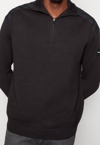 Maglione nero a pullover con collo a zip, texture a costine, pannelli delle spalle a contrasto e vestibilità slim. Dettaglio logo discreto sulla manica.