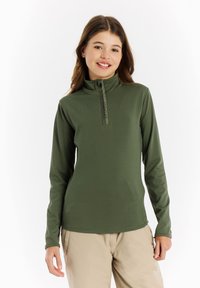 Langarm, half-zip top in donkergroen, met een opstaande kraag en een gladde textuur, gedragen met lichte broek.