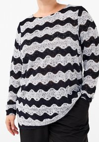 Sweter z dzianiny koronkowej w faliste czarno-bia�łe paski. Okrągły dekolt i długie rękawy. Tkanina ma strukturalny, otwarty splot.