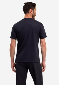 Donkerblauwe T-shirt met korte mouwen, gemaakt van zachte stof, met een eenvoudig ontwerp en gestikte accenten bij de schouder. Standaard pasvorm.