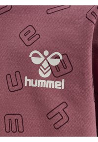 Bordeaux sweatshirt med en vit "hummel" logotyp och en bi-grafik, placerad mot en bakgrund av upprepande mörklila bokstäver och former.