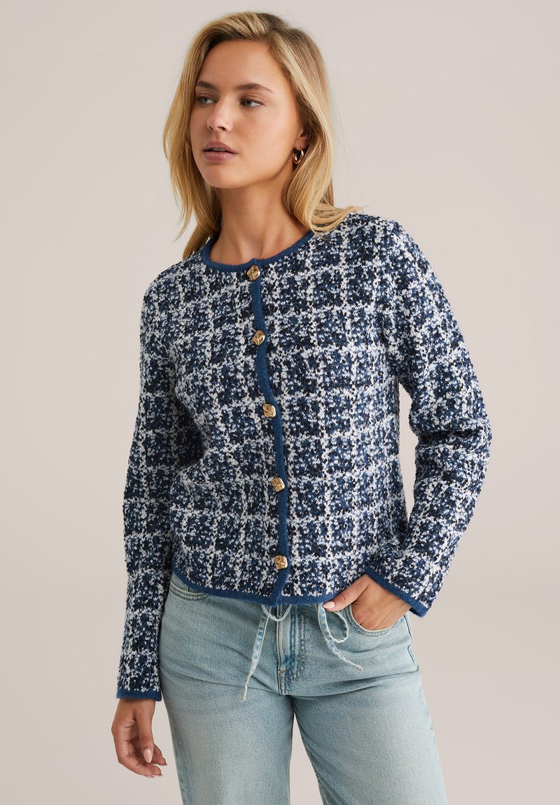 Navy and white patterned cardigan with a round neckline, long sleeves, and five golden buttons down the front. Soft knit texture.
