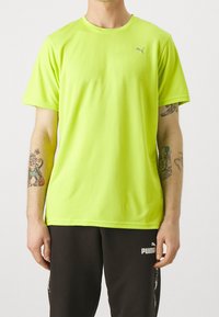 Neon žluté sportovní tričko s krátkým rukávem vyrobené z tkaniny odpařující vlhkost, s žebrovanou strukturou a malým logem Puma na hrudi.