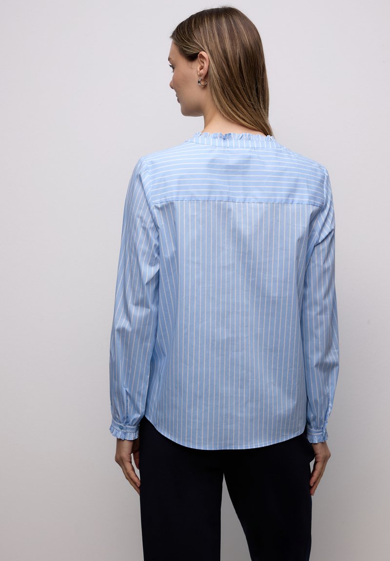 Chemise bleu clair à manches longues avec des rayures verticales blanches, dotée d'un ourlet arrondi, d'un col froncé et de poignets élastiqués.