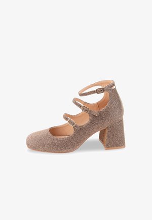 Zapatos Mary Jane en un brillante tono rosa dorado con tres correas de tobillo ajustables y un tacón grueso, que presentan un upper de tejido texturizado y puntera redondeada.