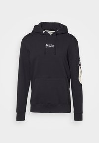 Czarna bluza z kapturem, z troczkami, przednią kieszenią i kieszenią na zamek z boku. Posiada biały nadrukowany logo na klatce piersiowej oraz metkę z tkaniny na rękawie.