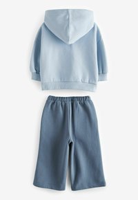 Világoskék kapucnis pulóver rugalmas mandzsettákkal és sötétkék rövidnadrág rugalmas derékszíjjal, mindkettő puha, jersey anyagból készült.