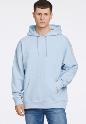 Ljusblå hoodie med en framficka, dragsko på huvan och en diskret logotyp över bröstet. Gjord av mjukt tyg med en avslappnad passform.