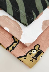 Három pamut póló egymásra rakva: fekete-zöld csíkos, fehér pink kamuflázs mintás, és rózsaszín fekete-sárga grafikával.