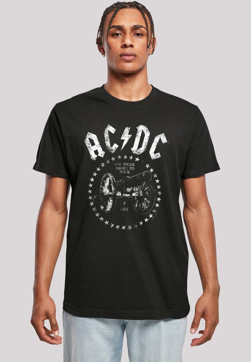 Black cotton T-shirt featuring a distressed AC/DC logo and cannon graphic with stars, creating a bold, graphic design. Short sleeves, crew neck.