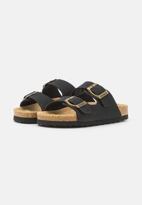Sorte slip-on sandaler i svart med to justerbare stropper, gullspenner og teksturert korksåle for komfort, satt på en slitesterk gummisåle.