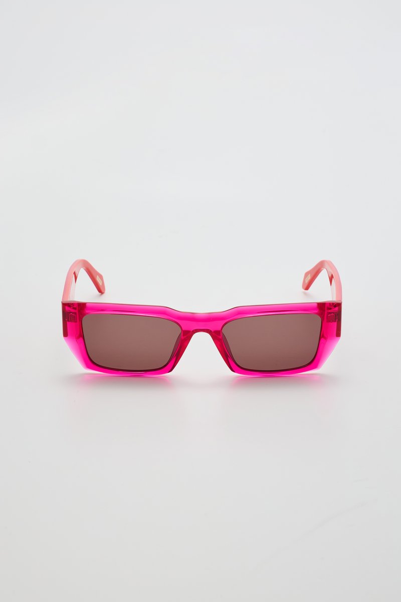 Lunettes de soleil transparentes roses avec des montures carrées, verres marron foncé et branches contrastantes rose clair. Pas de logos ou motifs visibles.