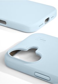 Lyseblåt silikone-telefonetui med udskæring til kamera, glat tekstur, afrundede kanter og trykt tekst "IDEAL OF SWEDEN."