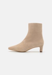 Beige semišové kotníkové boty s špičatou špičkou a krátkým blokovým podpatkem; hladká textura a jednoduchý design, bez viditelných kovových prvků nebo vzorů.