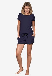 Granatowy zestaw krótki składa się z góry z krótkim rękawem o falbaniastych krawędziach oraz spodenek z koronkowym wykończeniem i satynowym sznurkiem.