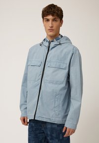 Chaqueta con capucha de color azul claro hecha de tela suave, con un cierre frontal completo, dos bolsillos en el pecho y un cordón en la capucha.