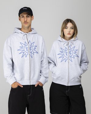 Grå zip-up hoodie med en blå solgrafik på fronten, med en hætte der har snore og kengurulommer, båret med sorte shorts.