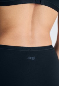 Black Sloggi underwear featuring a smooth, stretchy fabric with a seamless design. Subtle logo visible near the waistband.