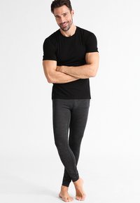 Svart tettsittende t-skjorte kombinert med mørke, teksturerte leggings. T-skjorten har korte ermer, og leggingsene har et subtilt ribbestrikket mønster.