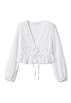 Blouse blanche courte à manches longues avec un décolleté en V profond, tissu texturé, taille froncée et deux cordons frontaux à nouer au niveau de la poitrine et de l'ourlet.