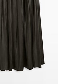 Abito lungo nero fluente in un tessuto liscio e lucido con texture plissettata; presenta una cintura arricciata e un orlo che curva dolcemente.