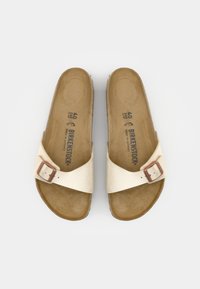 Paire de sandales beige Birkenstock avec une seule bride à boucle réglable et une semelle contournée vue de dessus.