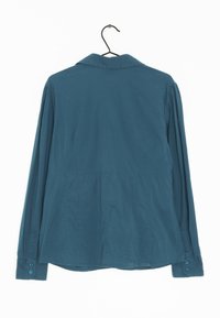 Camisetta a maniche lunghe color teal con collo a camicia, pannello posteriore arricciato e polsini bottonati. Realizzata in tessuto liscio con una texture semplice.