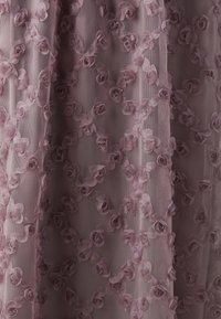 Kantstof in een zachte mauve kleur, met driedimensionale rozenapplicaties die in een bloemmotief op een doorschijnende achtergrond zijn gerangschikt.
