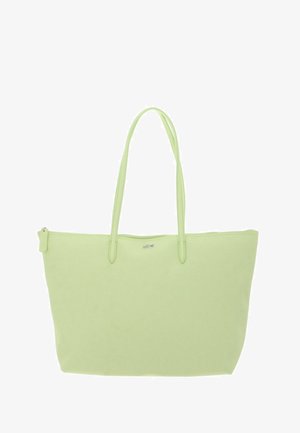 Sac cabas vert clair avec deux longues poignées, fermeture éclair sur le dessus et petit logo argenté au centre avant.