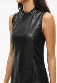 Zwarte leren mouwloze jurk met een hoge hals, een gladde textuur en een aansluitende pasvorm, met subtiele naaddetails langs de zijkanten.