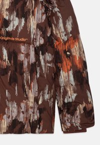 Doudoune marron avec des motifs abstraits en orange, noir et bleu clair. Comprend des sections cousues et un logo sur l'épaule.