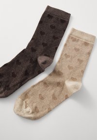 Pair of crew socks, one brown with darker heart patterns, the other beige with lighter hearts. Ribbed cuffs, soft texture.