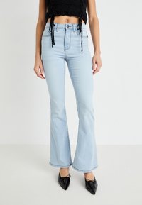 Lyseblå flarejeans laget av denim med høy midje, som har et klassisk fem-lomme-design, og kombinert med spisse svarte sko.