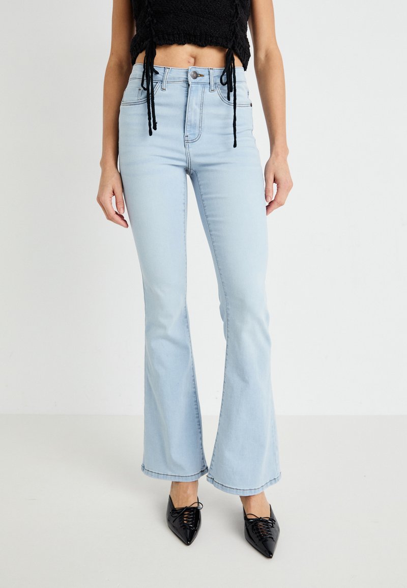 Lyseblå flarejeans laget av denim med høy midje, som har et klassisk fem-lomme-design, og kombinert med spisse svarte sko.