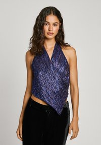 Top style halter en tissu violet irisé avec un design texturé et froissé. Présente un devant croisé en superposition et une silhouette courte.