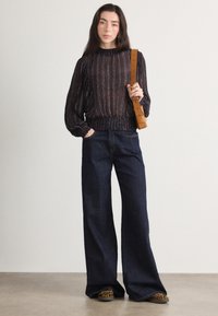 Blusa a fantasia navy con maniche a sbuffo, vita elastica e cinturino in cuoio marrone. Abbinata a jeans scuri con gamba larga e scarpe con stampa animalier.